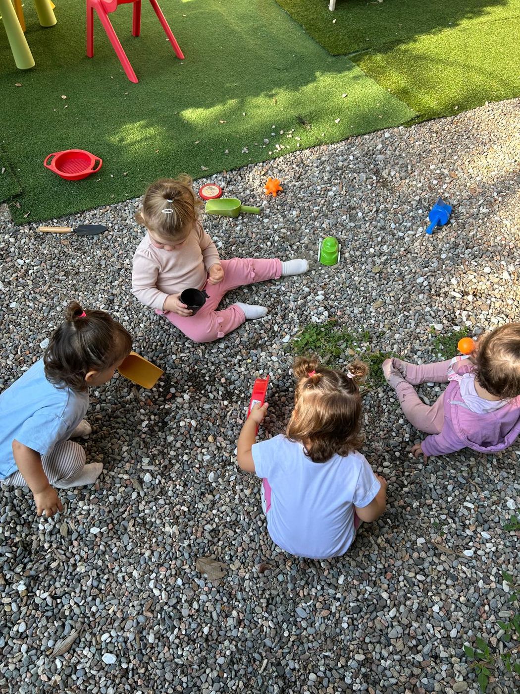 Un gruppo di bambini seduti insieme sulla ghiaia del giardino