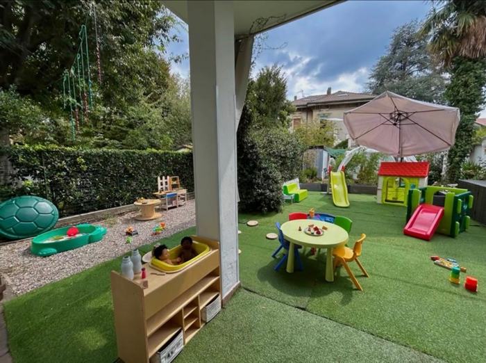 Il giardino visto dal portico, con tavolino, scivoli e casetta