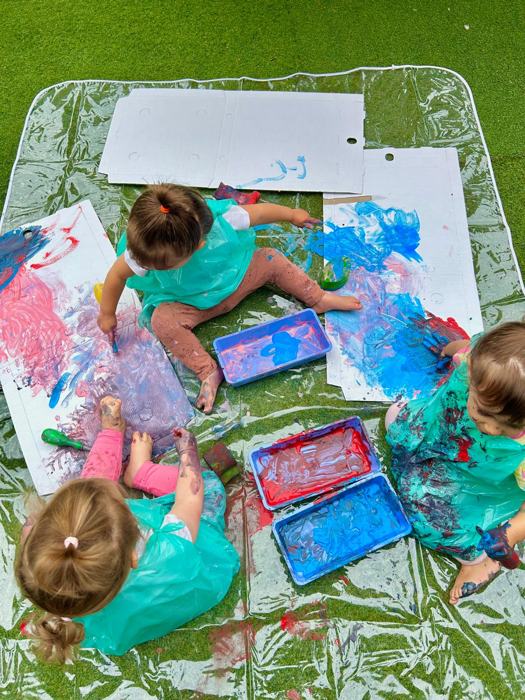 Bambini che dipingono con le mani su grandi fogli bianchi