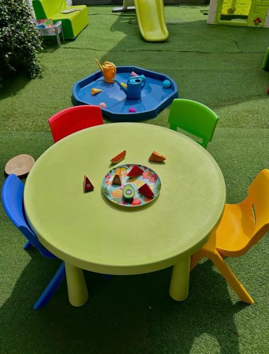 Tavolino verde con sedioline colorate nel prato