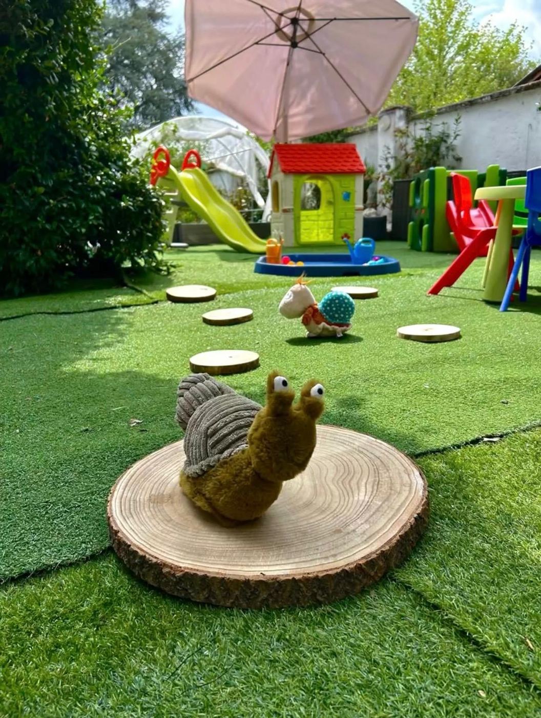 Una lumaca di peluche su un tronchetto in mezzo al prato del giardino